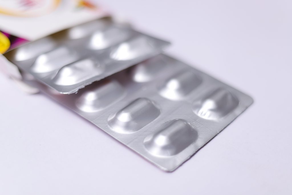 Primo piano di un blister argentato vuoto utilizzato per il confezionamento di compresse farmaceutiche su sfondo chiaro