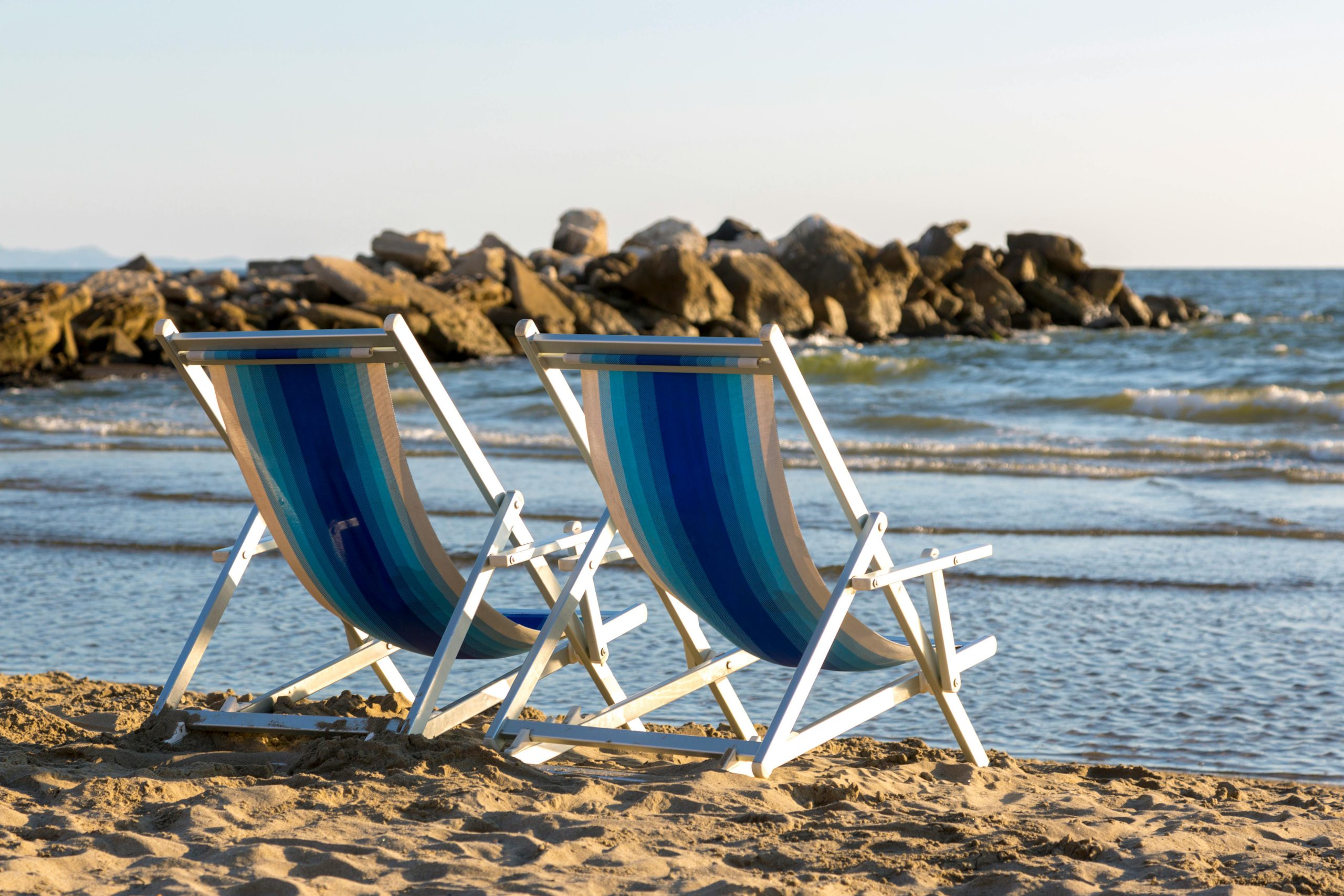 Due sedie a sdraio vuote in riva al mare, a simboleggiare il periodo di pausa dall'allenamento e il relax in vacanza
