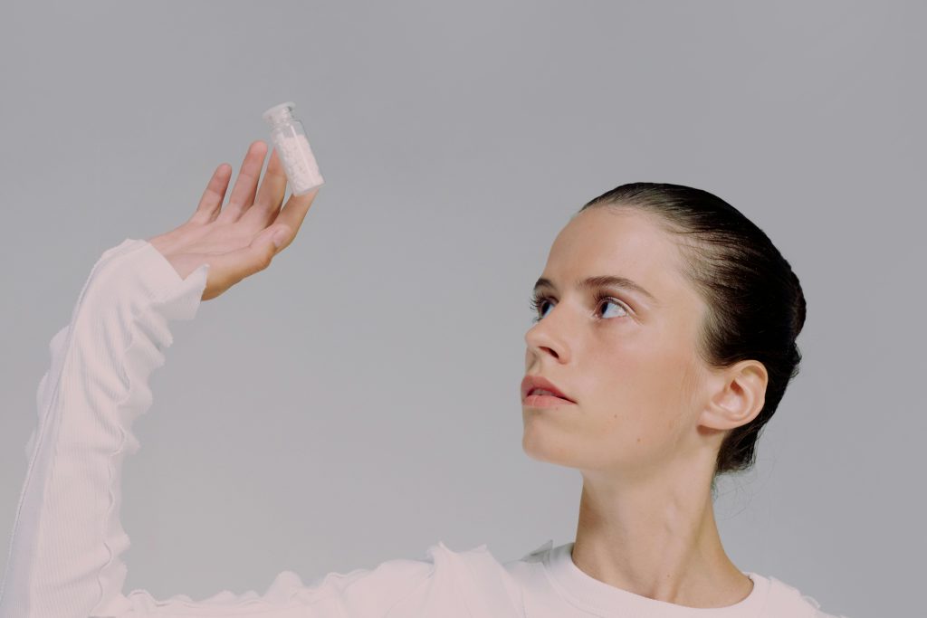 Giovane donna che osserva attentamente una fiala, a simboleggiare la ricerca scientifica e le nuove terapie a base di peptidi per il dolore cronico