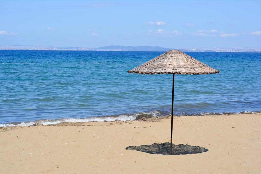 Una spiaggia soleggiata con un ombrellone, che rappresenta l'esposizione ai raggi UV e la necessità di riparare la pelle dal fotoinvecchiamento